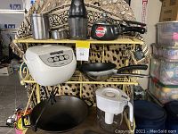 Wide view showing the shelving unit with all items arranged including the white rice cooker, black cast iron pan, white water filter pitcher, stainless steel containers, Hawkins pressure cooker, and Ninja grinder.