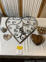Full view of all five heart-shaped items arranged on table: large metal scrollwork heart, music box, Las Vegas trinket holder, solid wood heart box, dried flowers heart container