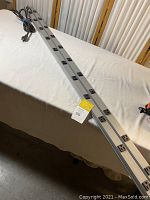 Two long silver Wiremold power strips with multiple black outlets resting on a table, with attached cords visible.