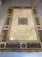 Full view of the beige, black, and gold Chateau rug featuring central medallion and detailed border.