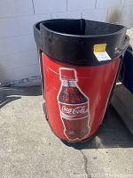 Photo of Coca Cola branded novelty ice chest, showing a large Coca Cola bottle graphic on red background, plastic body with open top.