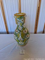 Front view of large ceramic vase showing white flowers and two twisted handles