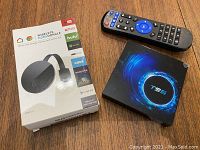 Photo showing the wireless HDMI dongle box, T95 media box, and remote control on a wooden surface.