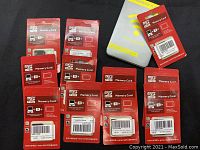 Ten red blister-packaged microSDHC cards with adapters and a steel storage tin.