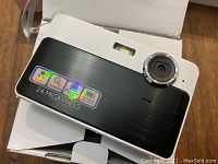 Close-up of a digital camera with 2.4 MP sticker, black and silver in color, showing lens and flash