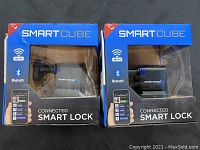 Two SmartCube connected smart locks in original packaging, showing front of boxes with product name and device visible.