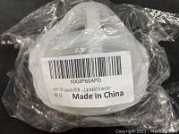 White molded mask with breathing valve in sealed plastic packaging with barcode label showing 'Made in China'.