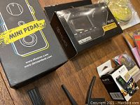 Donner Dark Mouse mini guitar pedal with box, KLIQ Metropitch tuner box, and accessories including patch cables and cables wrapped in plastic.