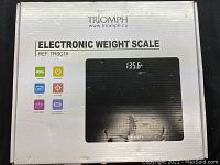 Box of the Triomph electronic weight scale model TRSC18 showing packaging, branding, and specs on the box front.