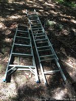 Photo showing both ladders laid on ground outdoors under light shade, illustrating full length and relative sizes.