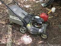 Craftsman lawn mower with grass catcher and red gas can on ground outdoors