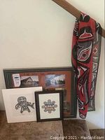 Group shot of three matted art prints leaning on a wall with red and black scarf draped