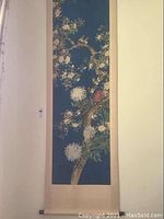 Full view of the wall hanging showing the floral and bird motif on a blue panel with beige border.