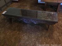 Top angle view showing the full table with glass top and carved wood body