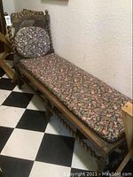 Full view of the wood carved chaise lounge with floral patterned cushion and rattan backrest showing condition and size.