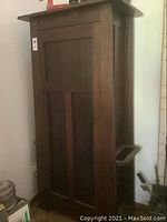 Front view of tall dark wood hall tree with panelled door and side umbrella stands