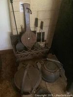 Wide shot showing cast iron kettle, pot with leather straps, bellows hanging on fireplace tool rack, and other fireplace tools.