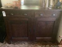 Front view of the wooden sideboard showing two drawers and two cupboard doors underneath. Dark wood with metal pull handles visible.