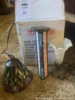 Tiffany style stained glass tulip light and two tabletop tulip glass shades with chain, showing complete lot on carpet.