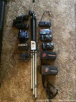 Photo showing Fuji cameras, tripod, binoculars, and accessories laid out on carpet.