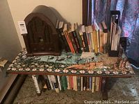 Photo of a vintage GE style AM/FM radio on a tapestry-covered small wooden table with books underneath