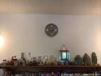 Full shelf view showing ceramic and brass vases, assorted owl figurines, a small mirrored display case, and additional items along the shelf.