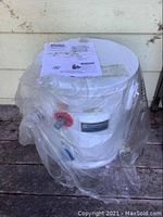 Kenmore water heater covered in plastic wrap with instruction sheet on top, showing it is new but stored.