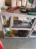 Shelf view of assorted hardware, extension cords, tool cases, and work gloves.