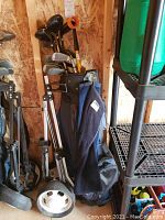 Full view of golf clubs in bag with attached towel and foldable golf caddy cart beside it