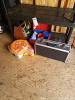Photo showing various yard games and sports equipment items including bocce ball case, washer toss set, golf balls, and lawn darts