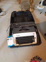 Front view of Olympia typewriter inside its open black plastic carrying case showing the keys and front panel.