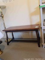 Full front view of the wooden sofa table showing the flat top, turned legs, and stretcher support, with visible nicks on the surface.