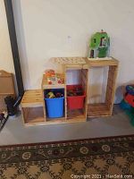 Photo showing three connected wooden cube organizers with two plastic bins and assorted toys on top and inside.