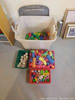 Entire lot showing four plastic bins with assorted wooden and Mega blocks.