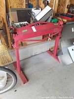 Full view of red sheet metal brake on stand