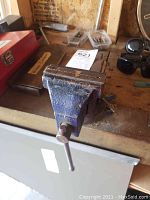 Front angled view of the metal bench vise showing the scuffed blue paint and the handle.