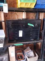 Front view of the black metal toolbox showing multiple drawers with recessed handles and top handle with latches