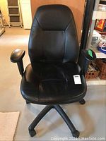 Front view of black adjustable office chair showing padded seat, backrest, armrests, and wheeled base.