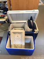 Three blue and white plastic coolers stacked, with a white ice pack inside one cooler