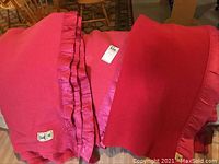 Three folded Kenwood wool blankets laid out side by side showing the red wool material and ruffled satin edges along with Kenwood brand labels.