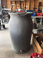 Front side view of gray plastic rain barrel with spigot at bottom.