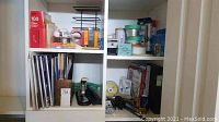 Shelves with various office supplies including folders, staplers, file organizers, tape, and pencil sharpener.