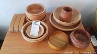 Eight wood bowls of various sizes and finishes arranged on a surface, showing surface scratches and wear.