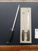 Full view of the sharpening steel with black handle and the boxed carving fork and slicer knife.