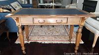 Front view showing rectangular top with blue leather inset and central drawer with brass bail handle
