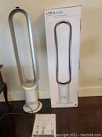 Dyson Cool tower fan on floor next to its original box and manual
