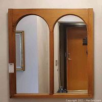 Front view of rectangular wooden framed mirror with two arched mirror panels.