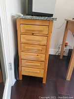 Front view of wooden chest of drawers with six drawers and granite top.