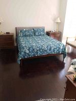 Full view of assembled bed with comforter and pillows on hardwood floor