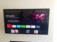 Front view of TV powered on showing Google Play interface and app icons